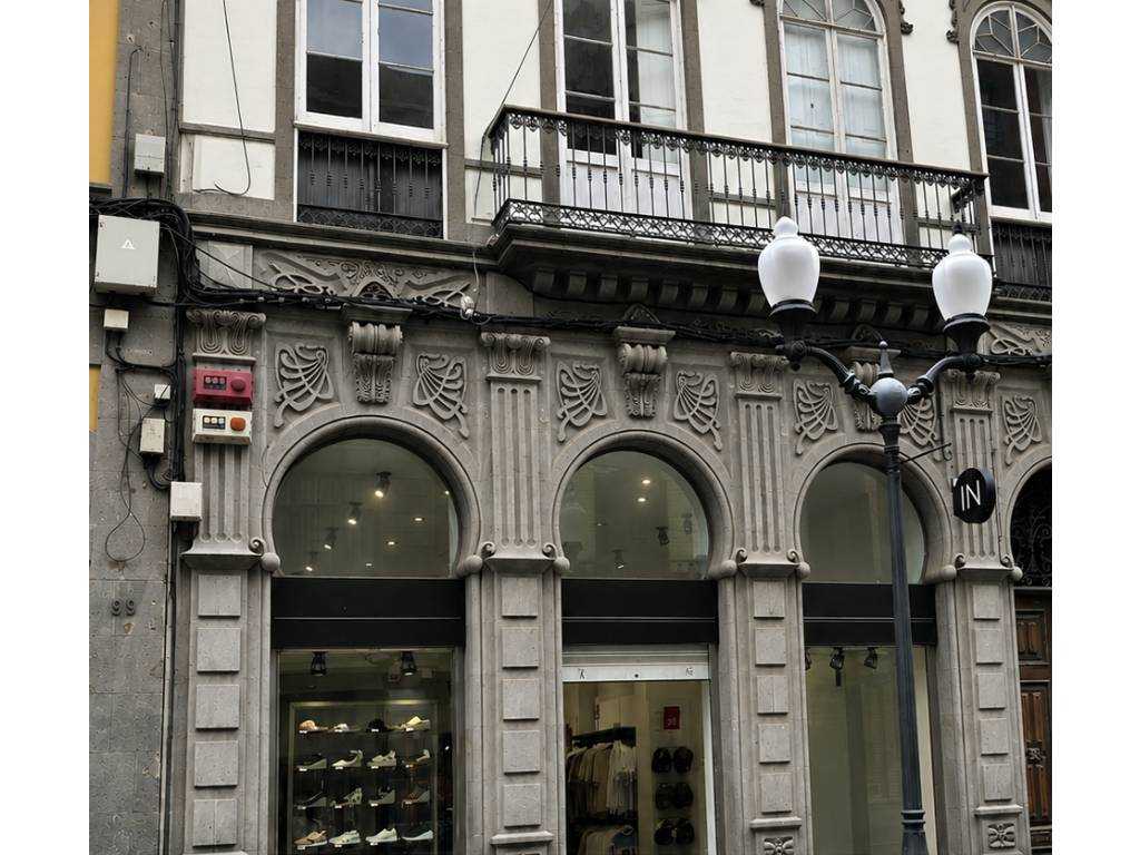 Elektroinstallation an der Fassade eines Geschäftsgebäudes mit zahlreichen außen verlegten Kabeln und Verteilerkästen