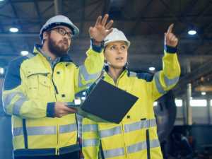 Sicherheitsbeauftragte im Betrieb besprechen Arbeitsschutzmaßnahmen in einer Produktionshalle